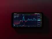 Автоматическая торговля криптовалютами — плюсы и минусы a cell phone displaying a stock chart on a red background