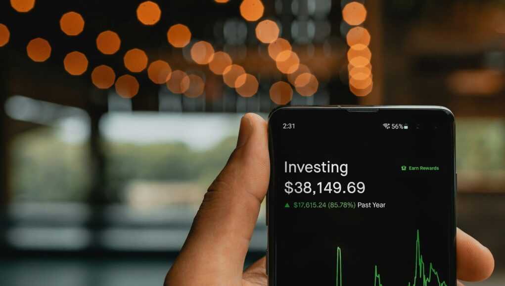 Как избежать мошенничества при инвестировании в крипто‑проекты a person holding up a cell phone with a stock chart on it