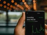 Как избежать мошенничества при инвестировании в крипто‑проекты a person holding up a cell phone with a stock chart on it